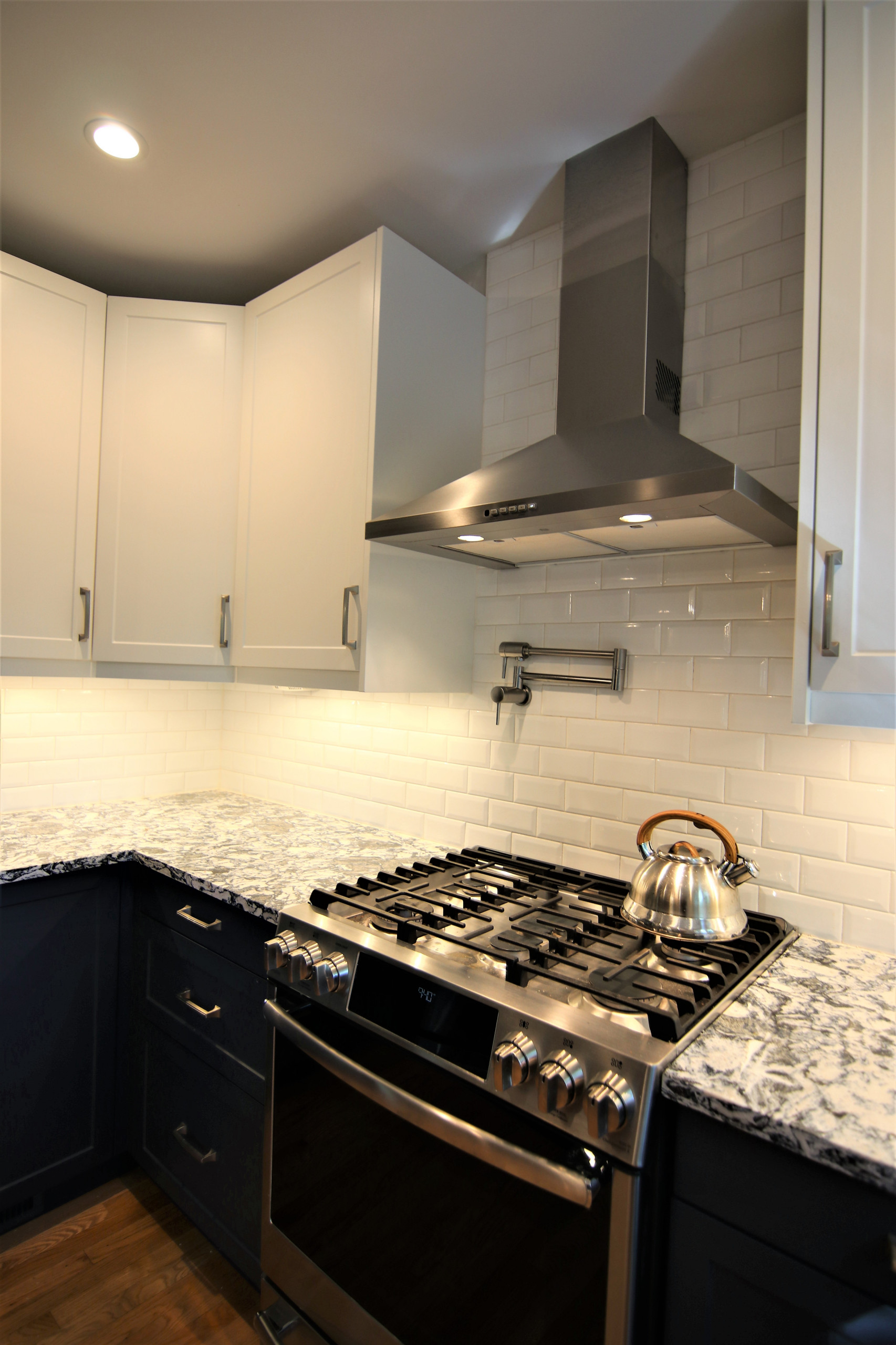 Kitchen - kitchen idea in DC Metro with a farmhouse sink, shaker cabinets, blue cabinets, quartz countertops, white backsplash, ceramic backsplash, stainless steel appliances and multicolored countert