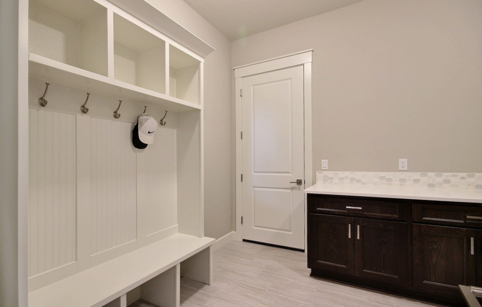 This is an example of a large modern u-shaped utility room in Portland with an undermount sink, recessed-panel cabinets, dark wood cabinets, quartz benchtops, white splashback, mosaic tile splashback, beige walls, ceramic floors, a side-by-side washer and dryer, grey floor and white benchtop.