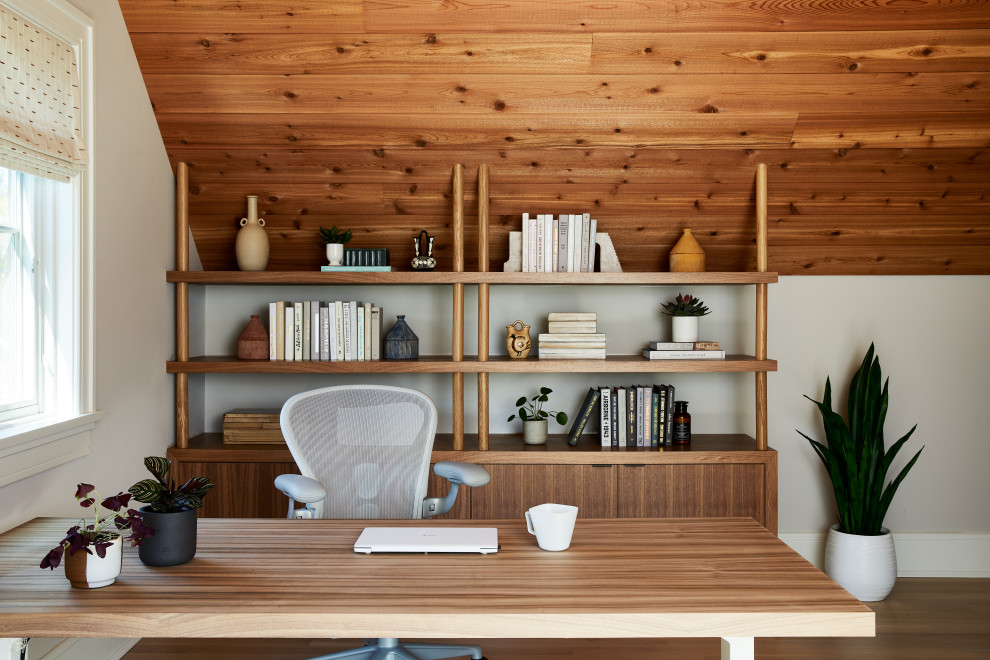 Bild på ett maritimt arbetsrum, med beige väggar, mellanmörkt trägolv, ett fristående skrivbord och brunt golv