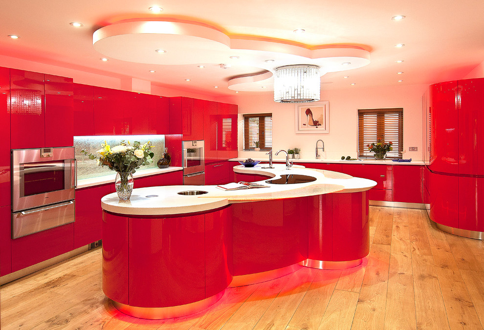 Expansive modern u-shaped separate kitchen in London with an integrated sink, flat-panel cabinets, red cabinets, solid surface benchtops, blue splashback, glass sheet splashback, stainless steel appliances, light hardwood floors and with island.
