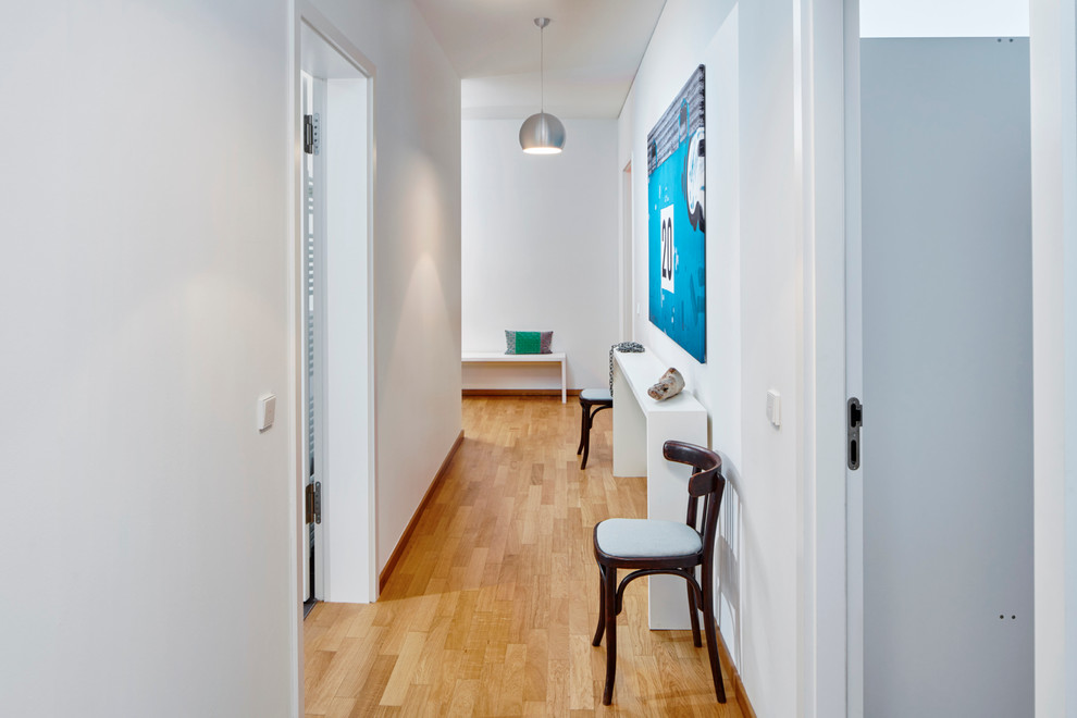 Design ideas for a mid-sized contemporary hallway in Hamburg with white walls and light hardwood floors.