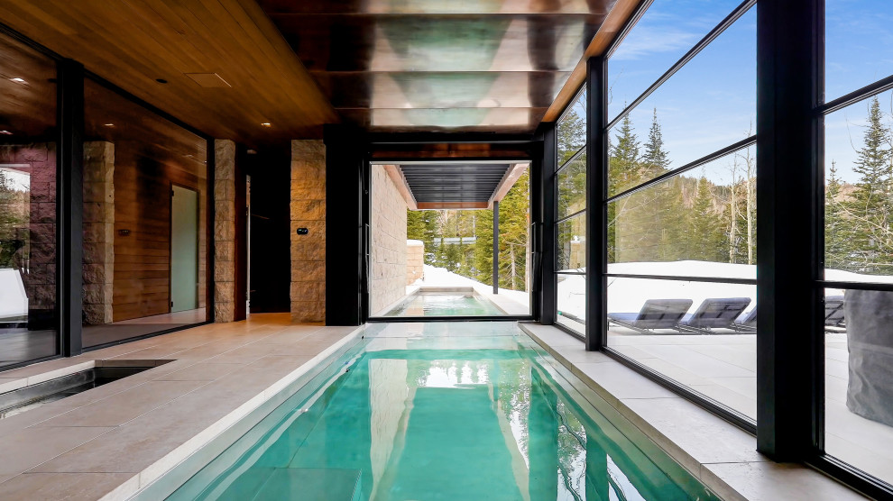 Photo of an expansive modern indoor rectangular lap pool in Salt Lake City with natural stone pavers.