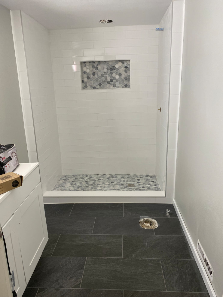 This is an example of a medium sized contemporary shower room bathroom in Other with flat-panel cabinets, white cabinets, a walk-in shower, a one-piece toilet, grey tiles, ceramic tiles, grey walls, terracotta flooring, a submerged sink, solid surface worktops, grey floors, a sliding door, white worktops, a wall niche, a single sink and a freestanding vanity unit.