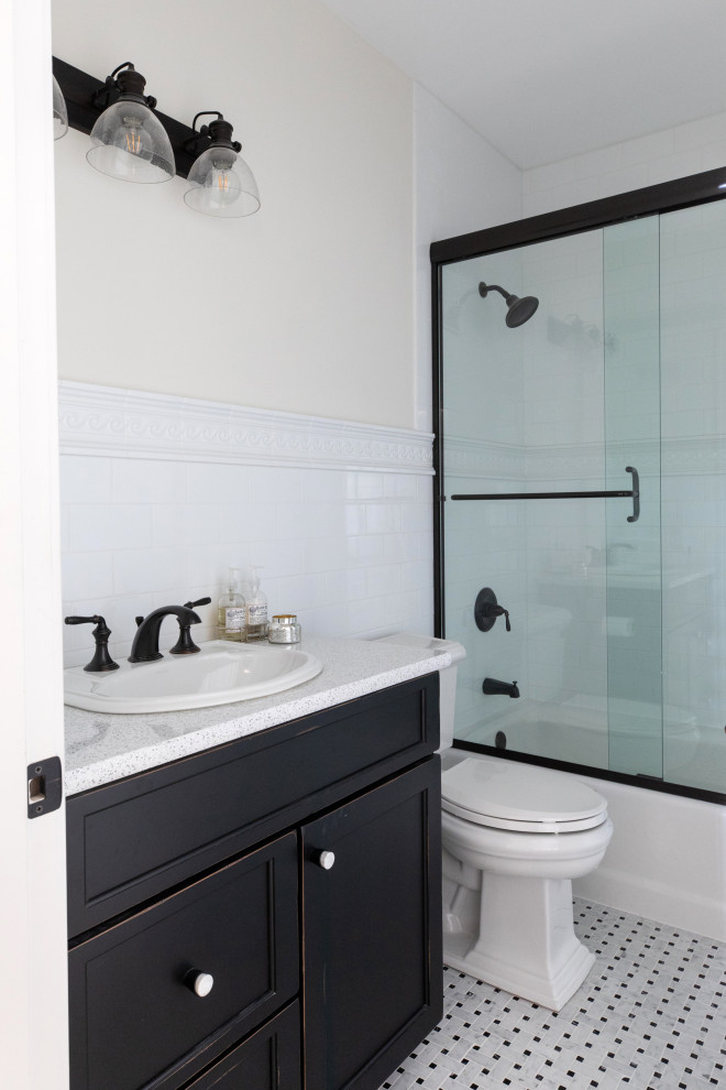 This is an example of a medium sized traditional shower room bathroom in Milwaukee with flat-panel cabinets, black cabinets, an alcove bath, an alcove shower, a two-piece toilet, white tiles, cement tiles, beige walls, mosaic tile flooring, a submerged sink, engineered stone worktops, white floors, a hinged door, white worktops, a single sink and a built in vanity unit.