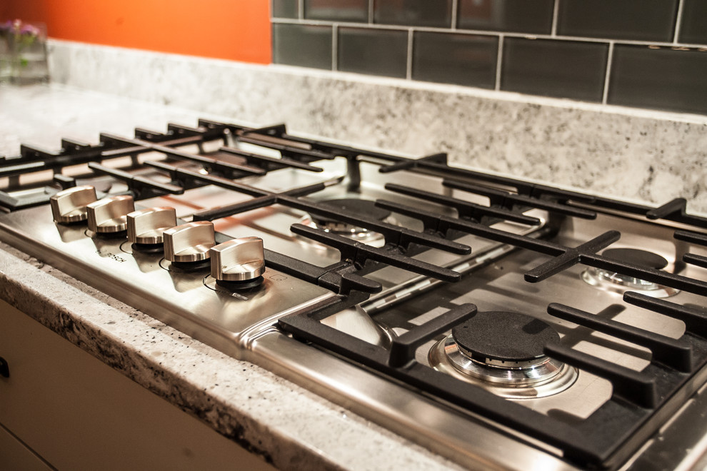 Example of a large transitional u-shaped light wood floor and brown floor enclosed kitchen design in Baltimore with an undermount sink, shaker cabinets, white cabinets, gray backsplash, subway tile backsplash, stainless steel appliances, an island and quartz countertops