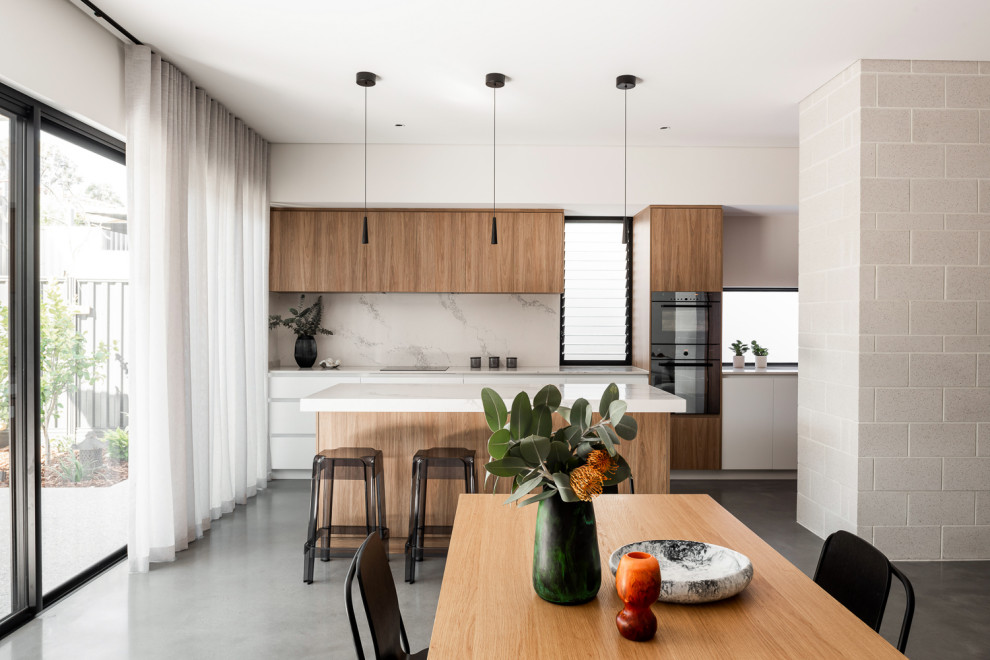 This is an example of a mid-sized contemporary galley open plan kitchen in Perth with flat-panel cabinets, medium wood cabinets, quartz benchtops, marble splashback, concrete floors and with island.