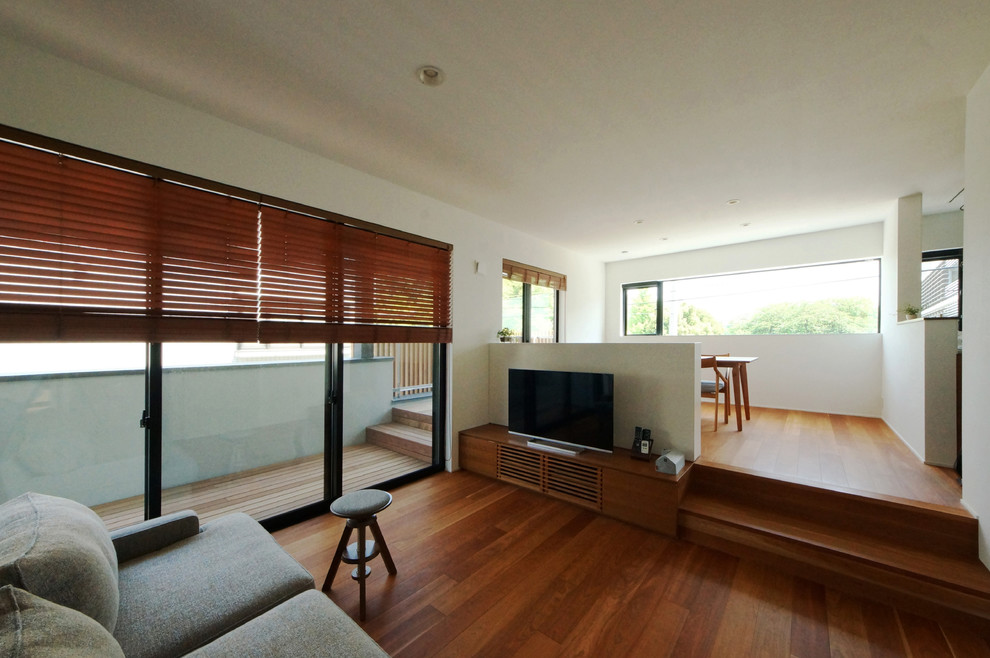 This is an example of a mid-sized modern formal open concept living room in Tokyo with white walls, medium hardwood floors, no fireplace and a freestanding tv.