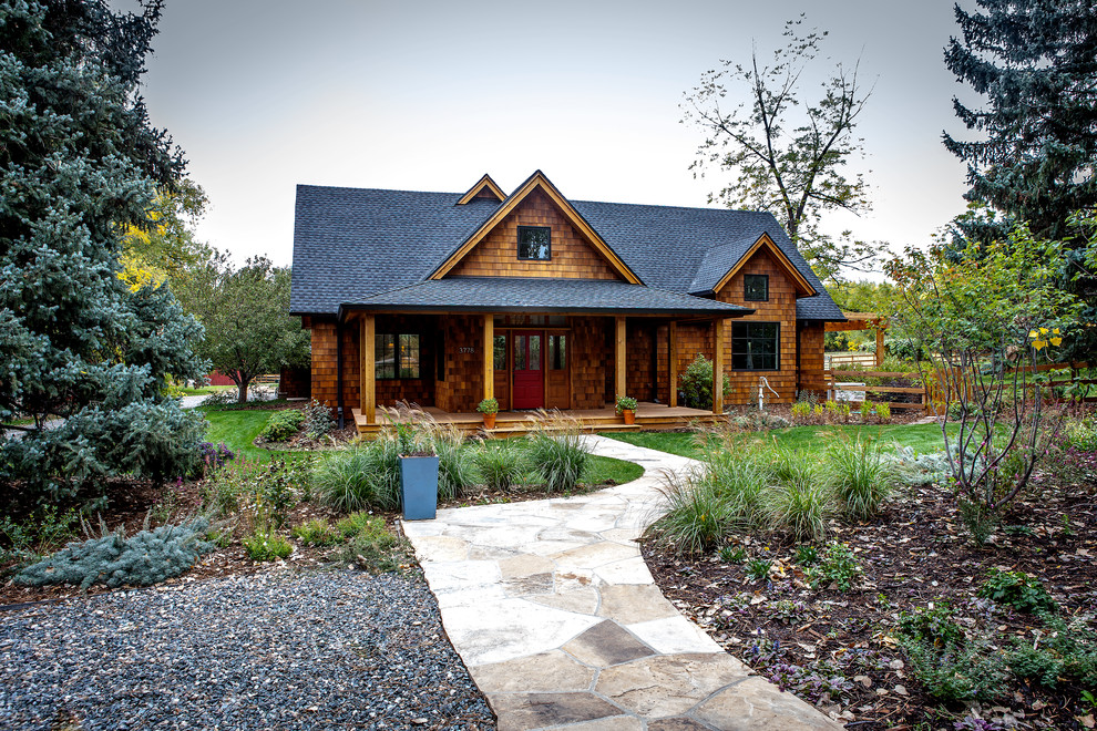 This is an example of a mid-sized country front yard full sun garden for spring in Denver with a garden path and natural stone pavers.