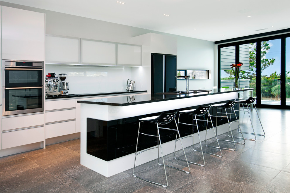 Design ideas for a large contemporary galley eat-in kitchen in Christchurch with a drop-in sink, granite benchtops, white splashback, glass sheet splashback, stainless steel appliances, ceramic floors and with island.