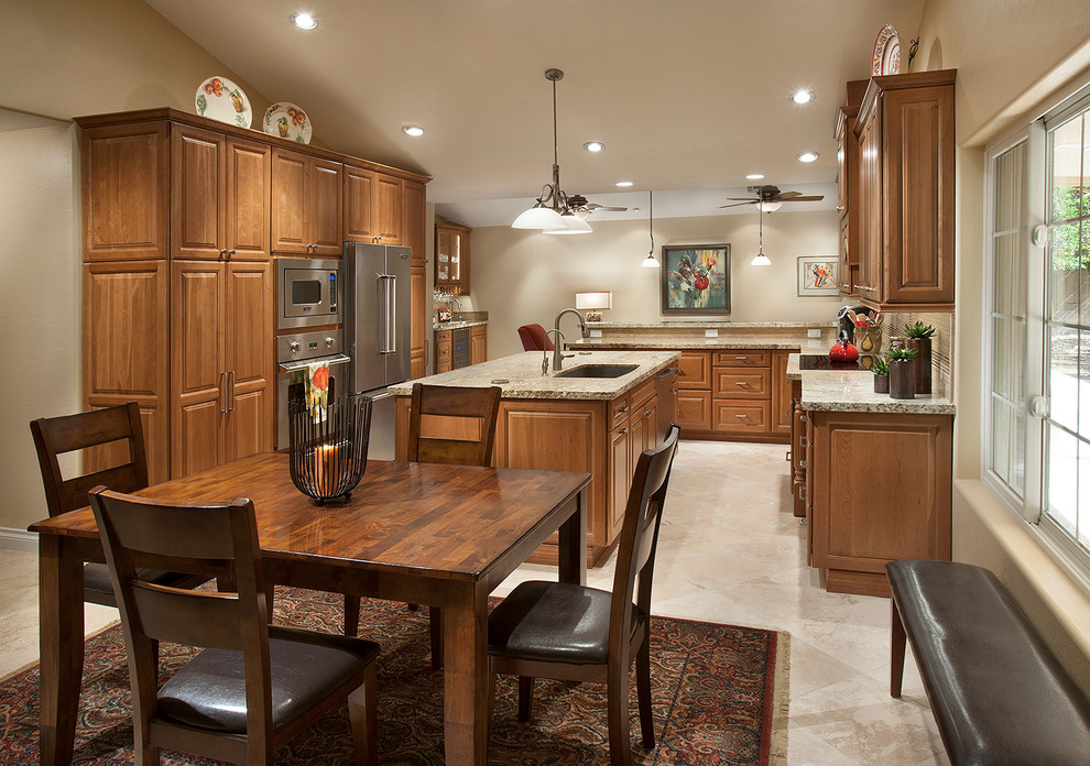Inspiration for a large transitional u-shaped travertine floor eat-in kitchen remodel in Phoenix with an undermount sink, beaded inset cabinets, medium tone wood cabinets, granite countertops, beige backsplash, stainless steel appliances and an island