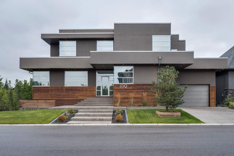 Inspiration for a contemporary three-storey grey house exterior in Calgary with mixed siding and a flat roof.