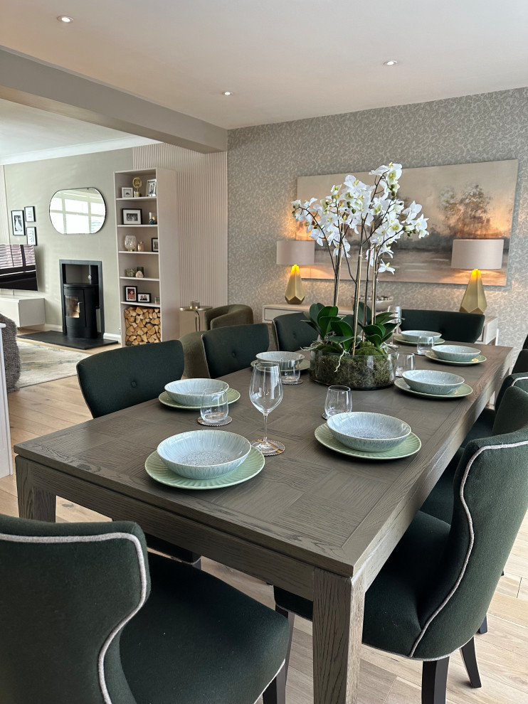 Design ideas for a large contemporary open plan dining room in Belfast with green walls, painted wood flooring, a wood burning stove, a metal fireplace surround, white floors and wallpapered walls.