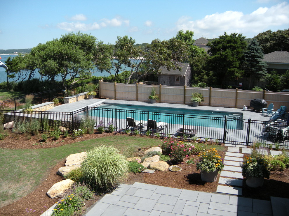 This is an example of a transitional backyard rectangular pool in Boston with a water feature and natural stone pavers.