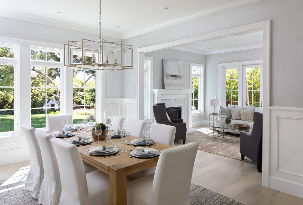 Inspiration for a large transitional separate dining room in San Francisco with grey walls, light hardwood floors, beige floor, a standard fireplace and a stone fireplace surround.
