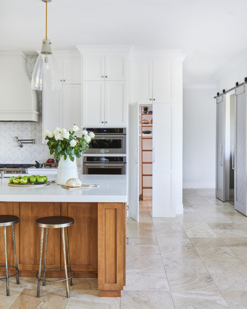 Design ideas for an expansive transitional kitchen in Other with an undermount sink, shaker cabinets, white cabinets, solid surface benchtops, white splashback, marble splashback, stainless steel appliances, travertine floors, with island, beige floor and white benchtop.