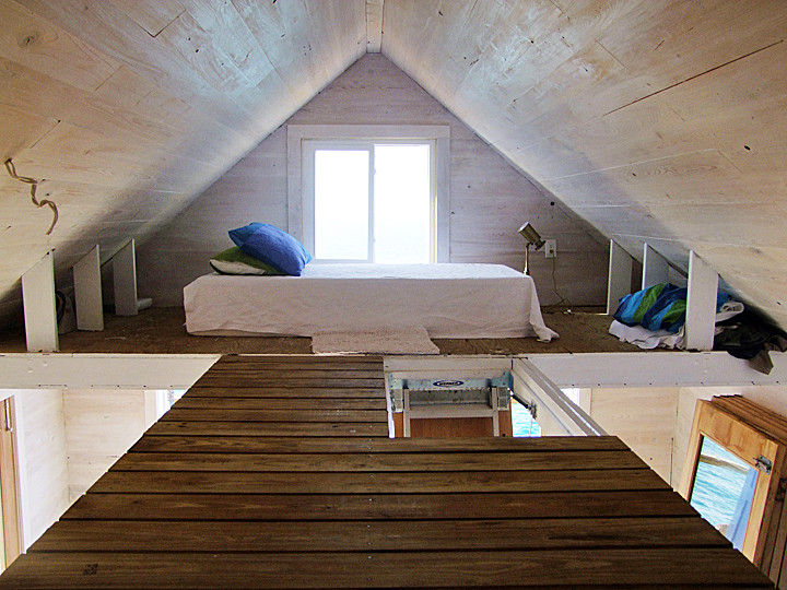 Small beach style loft-style bedroom in Other with beige walls and medium hardwood floors.