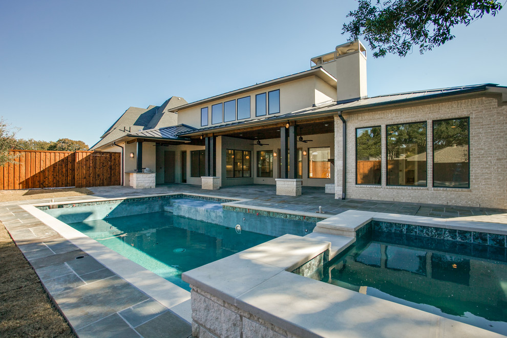 Photo of a large contemporary two-storey beige house exterior in Dallas with stone veneer, a hip roof and a metal roof.