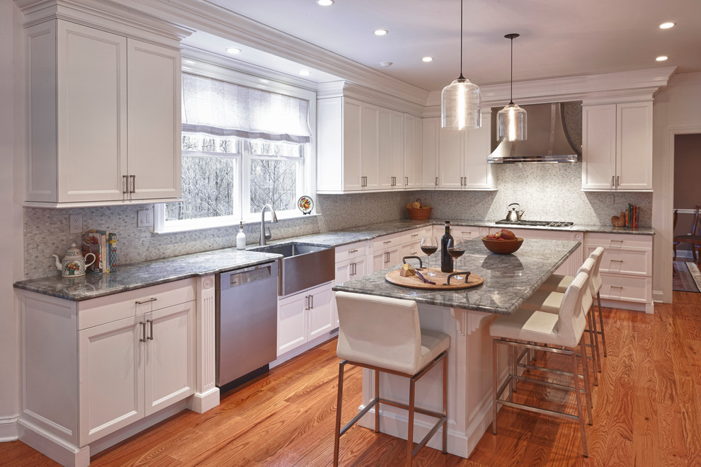 Kitchen pantry - large transitional medium tone wood floor kitchen pantry idea in New York with a farmhouse sink, shaker cabinets, white cabinets, quartzite countertops, white backsplash, mosaic tile backsplash, stainless steel appliances, white walls and an island