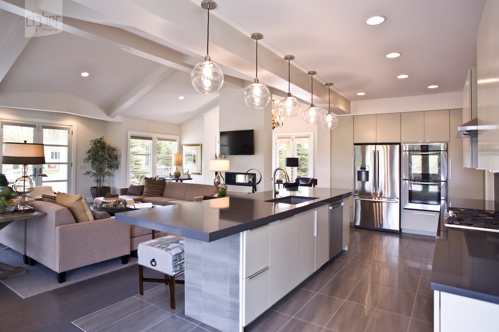Example of a large transitional l-shaped porcelain tile and gray floor open concept kitchen design with an undermount sink, flat-panel cabinets, gray cabinets, stainless steel appliances, gray walls, an island and quartz countertops