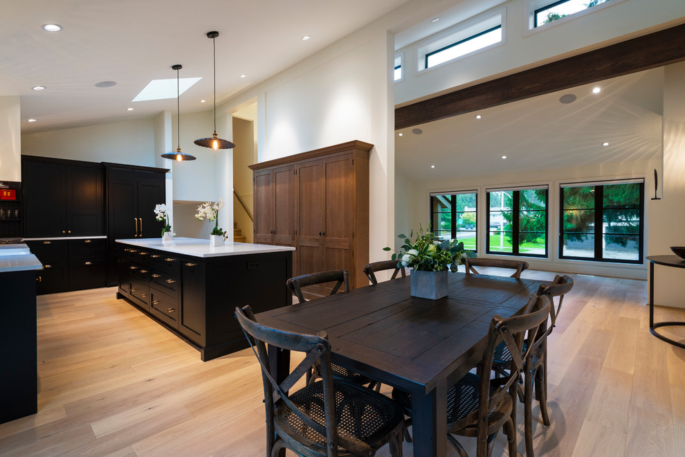 Inspiration for a mid-sized rustic l-shaped light wood floor and beige floor open concept kitchen remodel in Vancouver with a farmhouse sink, shaker cabinets, black cabinets, quartz countertops, paneled appliances, an island and white countertops
