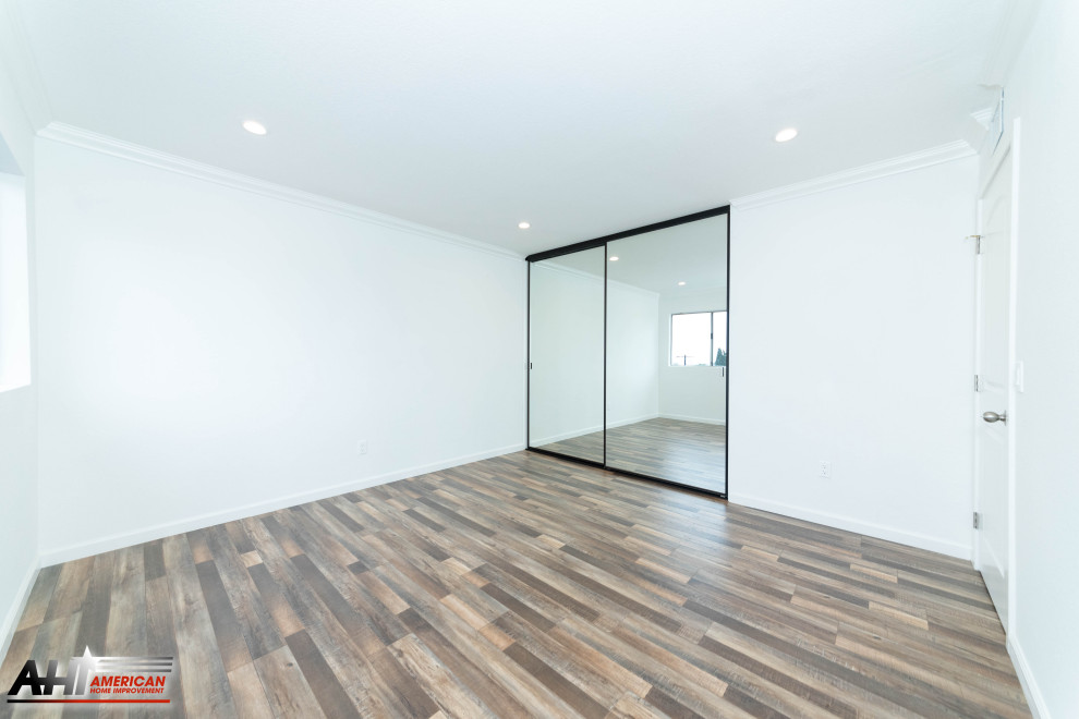Mid-sized modern guest bedroom in Los Angeles with white walls, medium hardwood floors and brown floor.