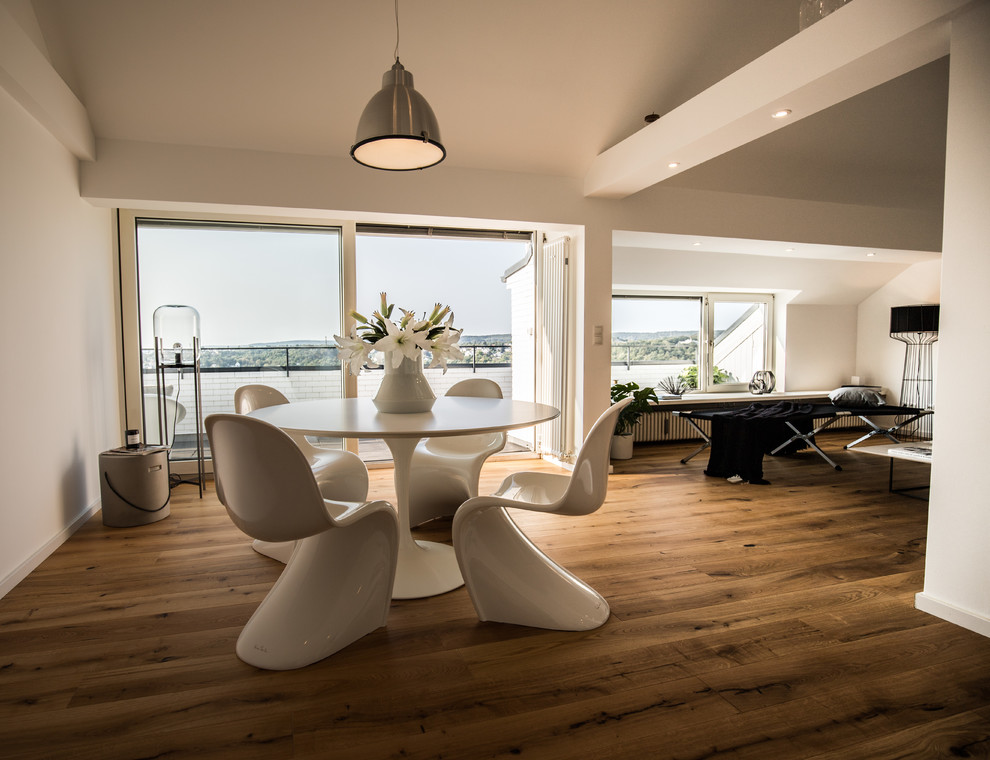 This is an example of a mid-sized contemporary open plan dining in Bonn with white walls, dark hardwood floors, no fireplace and brown floor.