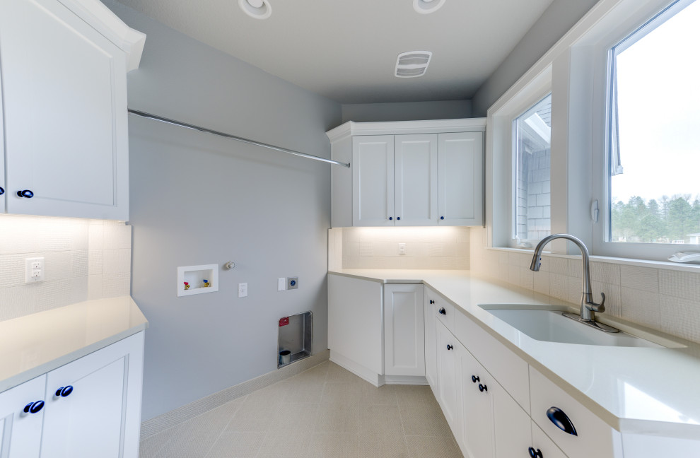 Photo of a mid-sized transitional galley dedicated laundry room in Portland with an utility sink, shaker cabinets, white cabinets, quartz benchtops, grey walls, porcelain floors, a side-by-side washer and dryer, grey floor and grey benchtop.