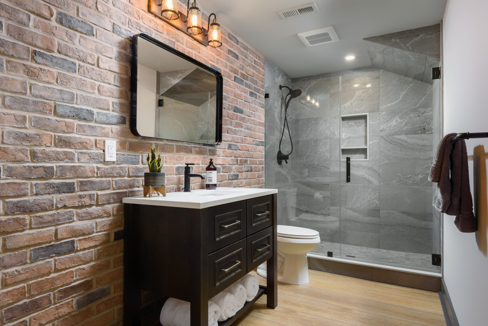 Design ideas for a mid-sized industrial 3/4 bathroom in Philadelphia with black cabinets, an alcove shower, a two-piece toilet, gray tile, porcelain tile, vinyl floors, an undermount sink, engineered quartz benchtops, beige floor, a hinged shower door, white benchtops, white walls and recessed-panel cabinets.