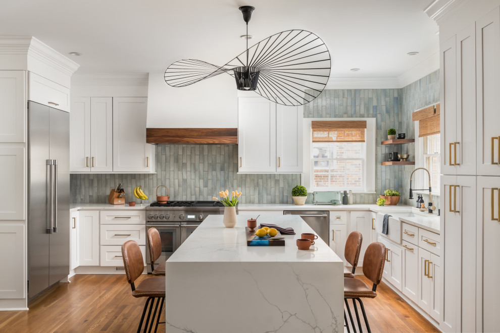 This is an example of a large transitional kitchen in Atlanta with a farmhouse sink, shaker cabinets, grey cabinets, quartz benchtops, blue splashback, cement tile splashback, stainless steel appliances, medium hardwood floors, with island and white benchtop.