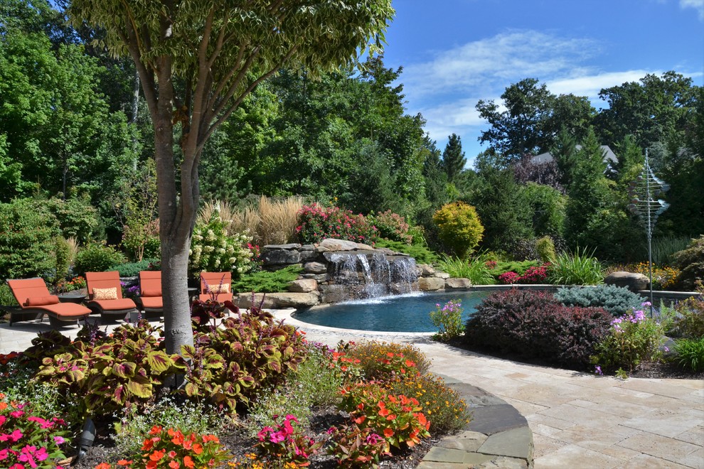 Photo of a large tropical backyard custom-shaped pool in New York with a water feature.