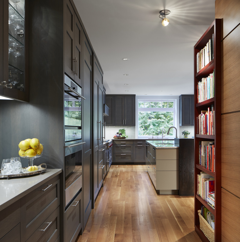 Eat-in kitchen - large transitional single-wall medium tone wood floor eat-in kitchen idea in Minneapolis with paneled appliances, an island, an undermount sink, shaker cabinets, gray cabinets, quartz countertops, white backsplash and ceramic backsplash