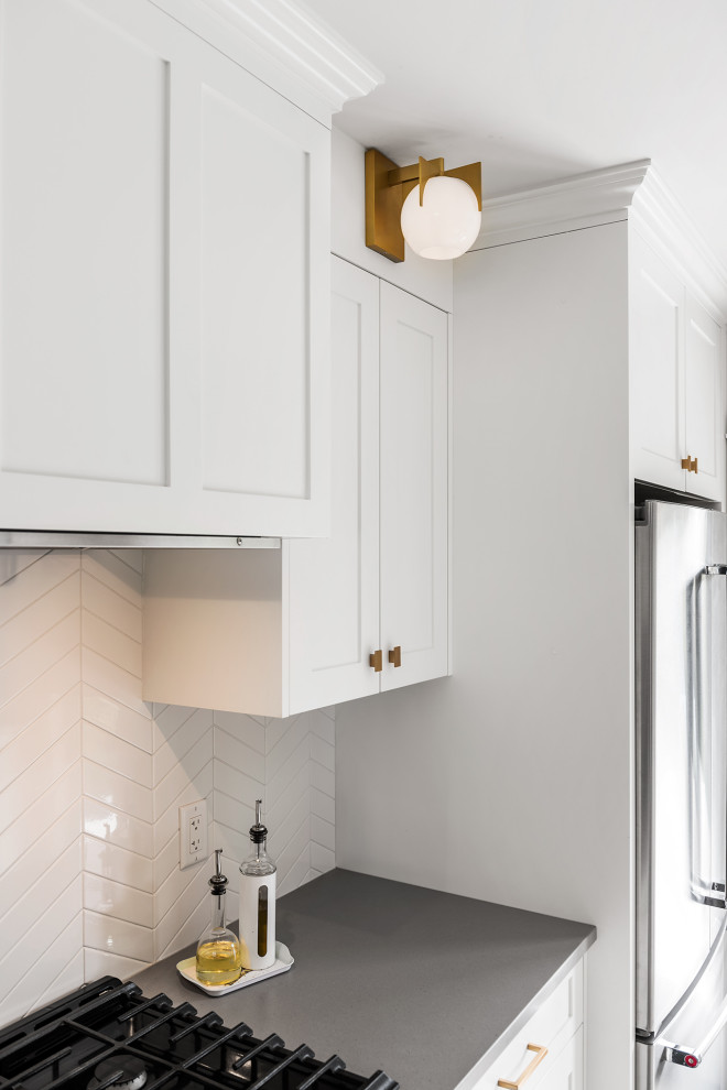 Mid-sized transitional galley light wood floor and gray floor eat-in kitchen photo with a double-bowl sink, recessed-panel cabinets, white cabinets, quartz countertops, white backsplash, ceramic backsplash, stainless steel appliances, no island and gray countertops