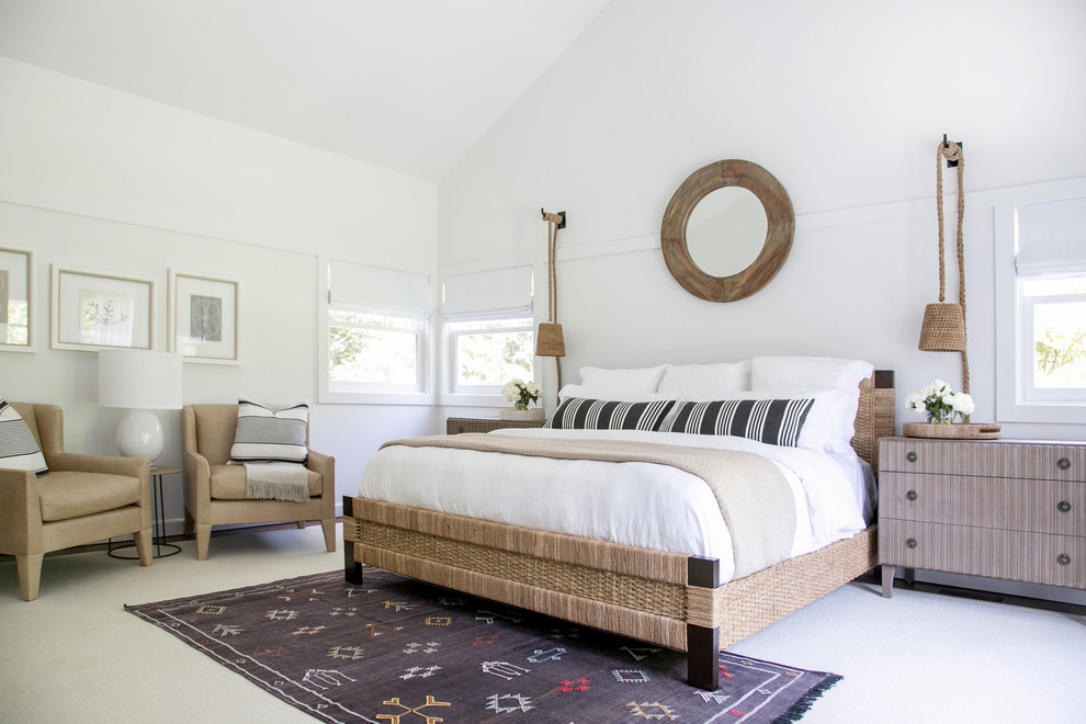 This is an example of an expansive beach style master bedroom in New York with white walls and medium hardwood floors.