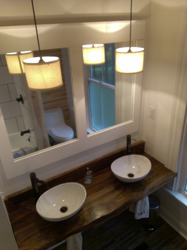 Photo of a small modern master bathroom in Cincinnati with wood benchtops, white tile, porcelain tile, a drop-in tub, a shower/bathtub combo, a one-piece toilet, a vessel sink, white walls and slate floors.