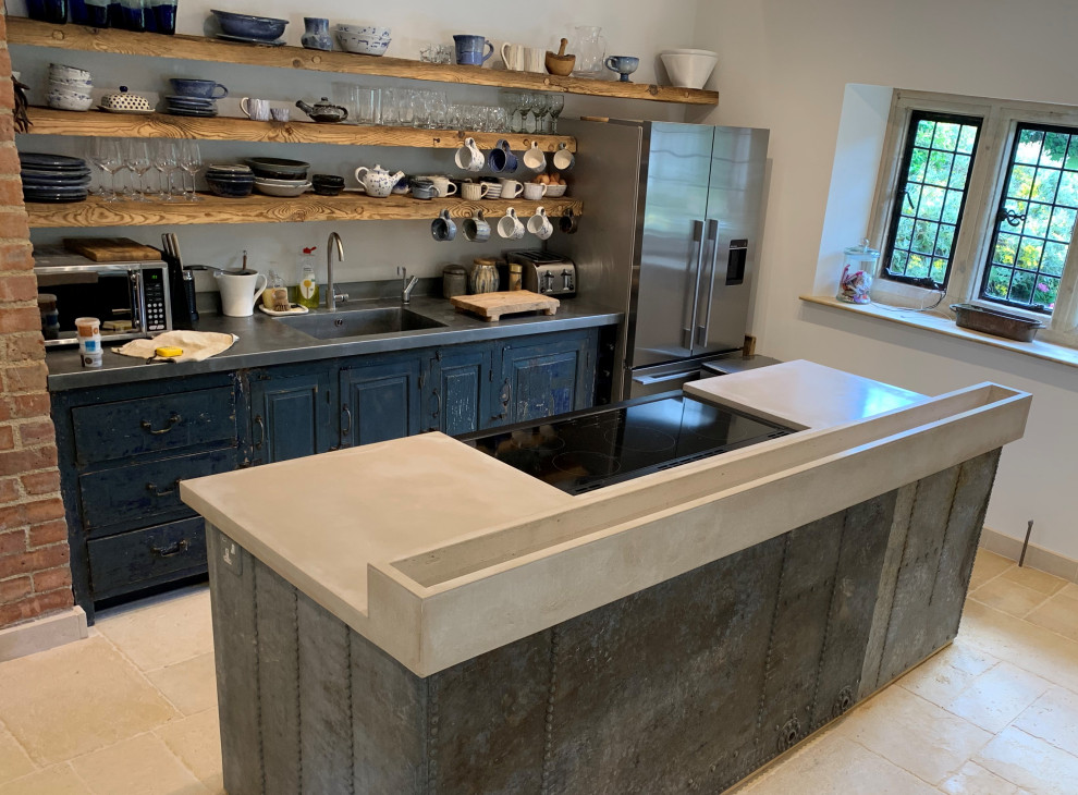 Design ideas for a large contemporary eat-in kitchen in Gloucestershire with distressed cabinets, concrete benchtops, grey splashback, black appliances, with island, beige floor and grey benchtop.