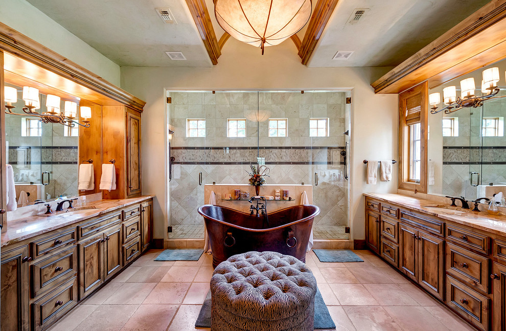 Inspiration for an expansive mediterranean master bathroom in Dallas with an undermount sink, dark wood cabinets, a freestanding tub, beige tile, beige walls, a double shower, travertine floors, brown floor, a hinged shower door, beige benchtops and recessed-panel cabinets.