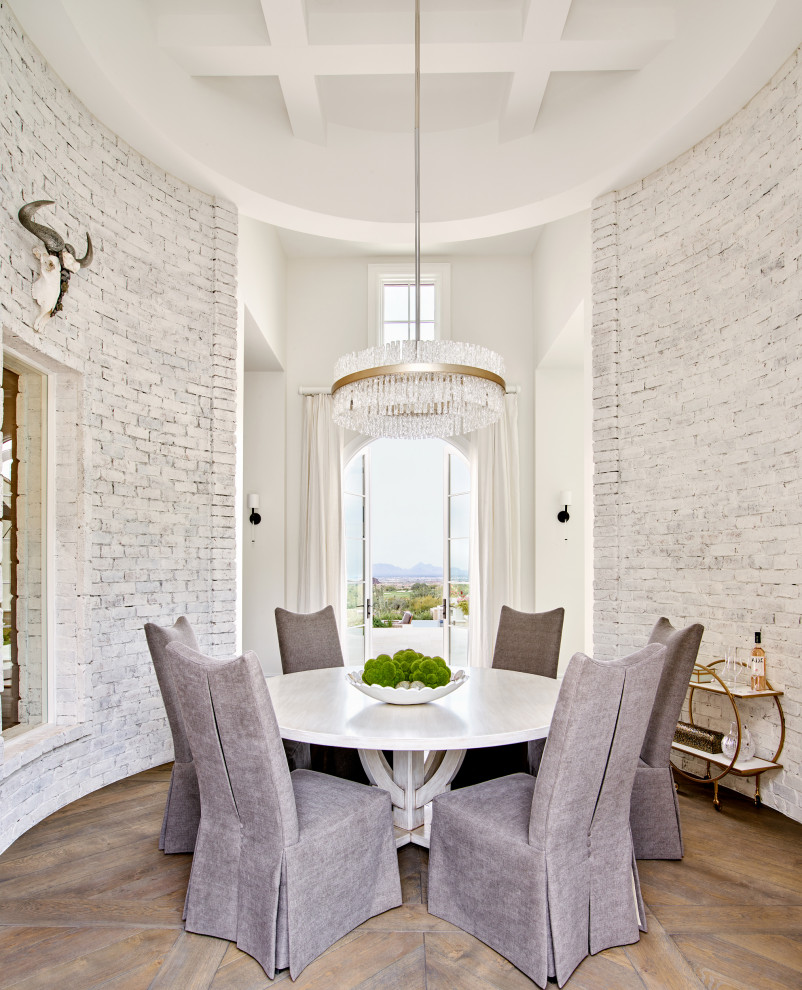 This is an example of a large mediterranean enclosed dining room in Phoenix with white walls, dark hardwood flooring, a coffered ceiling, brick walls and feature lighting.