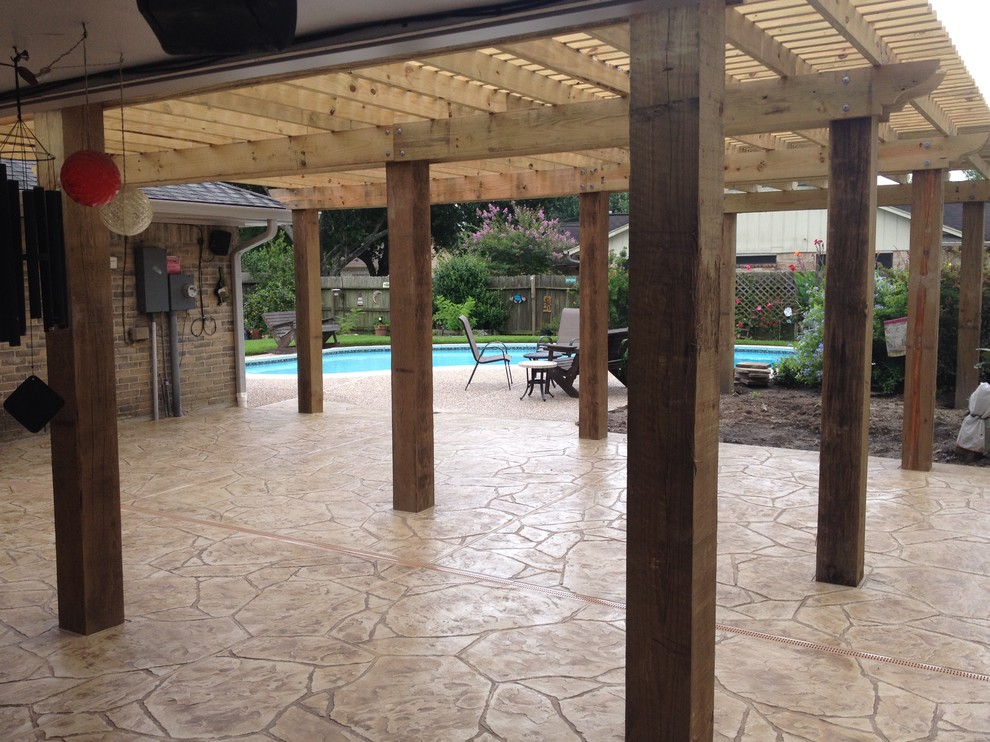 Large traditional backyard patio in Houston with stamped concrete and a pergola.
