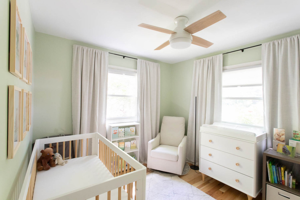 Imagen de habitación de bebé neutra actual pequeña con paredes verdes y suelo de madera clara