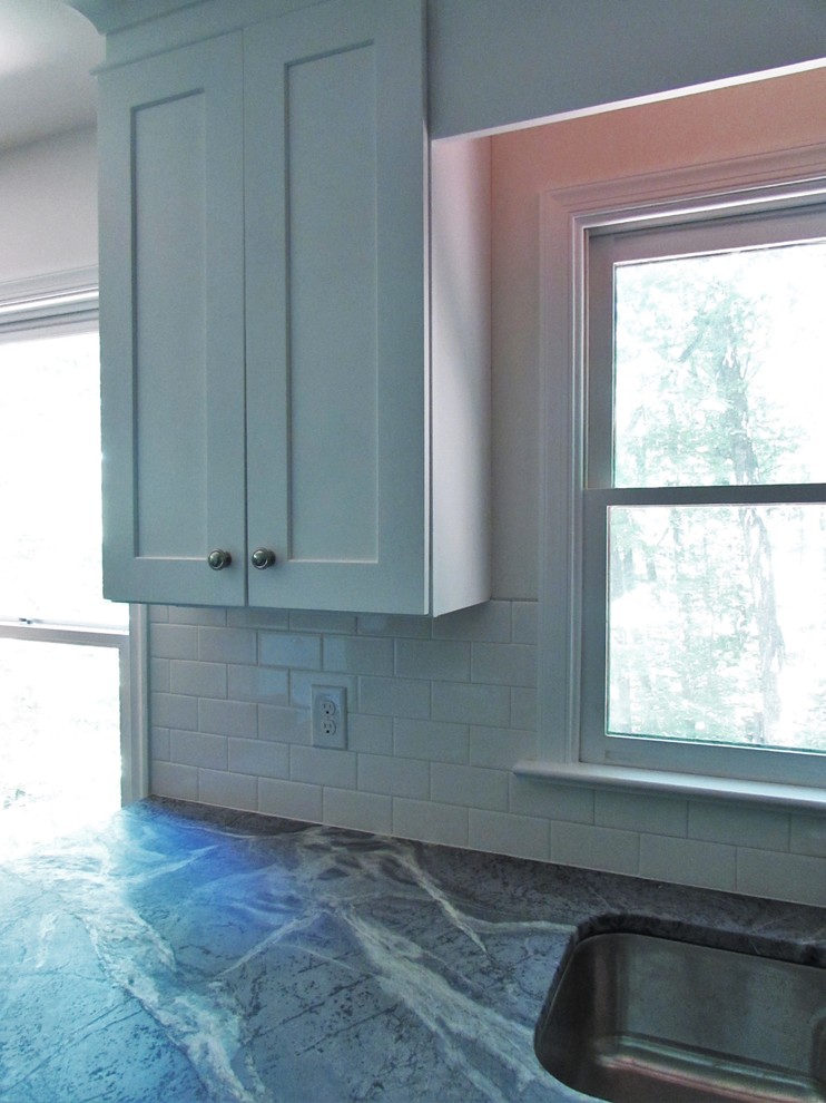 Enclosed kitchen - mid-sized transitional l-shaped medium tone wood floor enclosed kitchen idea with an undermount sink, shaker cabinets, white cabinets, soapstone countertops, white backsplash, subway tile backsplash, stainless steel appliances and a peninsula