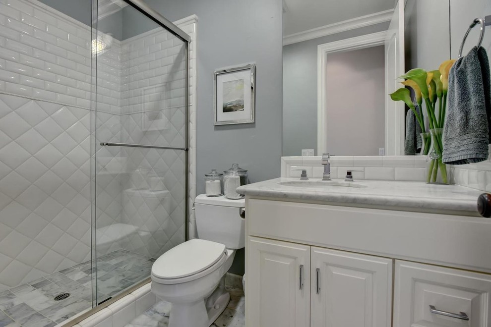 Mid-sized traditional 3/4 bathroom in San Francisco with raised-panel cabinets, white cabinets, an alcove shower, a two-piece toilet, white tile, porcelain tile, grey walls, marble floors, an undermount sink, engineered quartz benchtops, grey floor and a sliding shower screen.