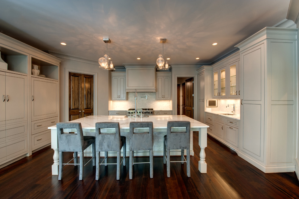 Open concept kitchen - large transitional u-shaped medium tone wood floor open concept kitchen idea in Atlanta with a farmhouse sink, beaded inset cabinets, white cabinets, marble countertops, white backsplash, porcelain backsplash, paneled appliances and an island
