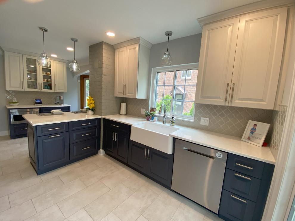 Mid-sized traditional l-shaped separate kitchen in Detroit with a farmhouse sink, raised-panel cabinets, white cabinets, quartz benchtops, beige splashback, ceramic splashback, stainless steel appliances, porcelain floors, a peninsula, beige floor and white benchtop.