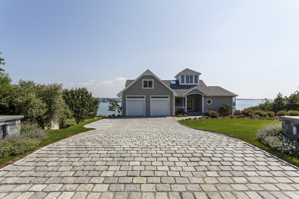 Mid-sized beach style front yard full sun driveway in Providence with natural stone pavers.