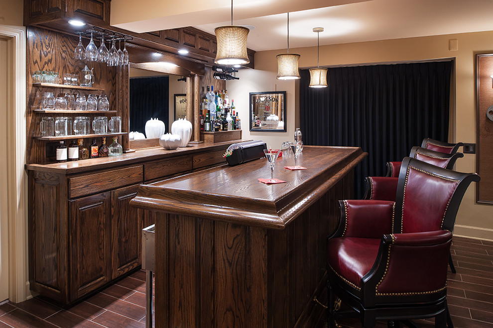 Photo of a mid-sized traditional single-wall seated home bar in New York with raised-panel cabinets, dark wood cabinets, wood benchtops, brown splashback, timber splashback, vinyl floors and brown floor.