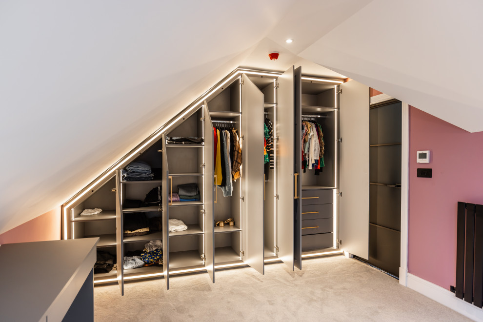 This is an example of a mid-sized contemporary gender-neutral storage and wardrobe in Buckinghamshire with shaker cabinets, grey cabinets, carpet and beige floor.