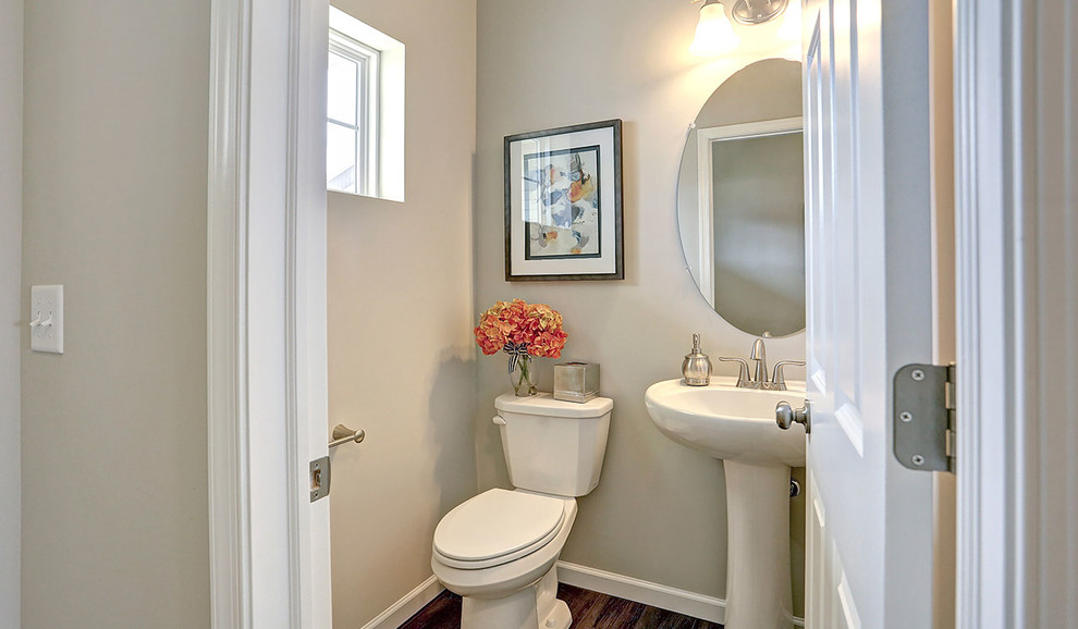 Photo of a mid-sized traditional powder room in Other with a two-piece toilet, grey walls and dark hardwood floors.