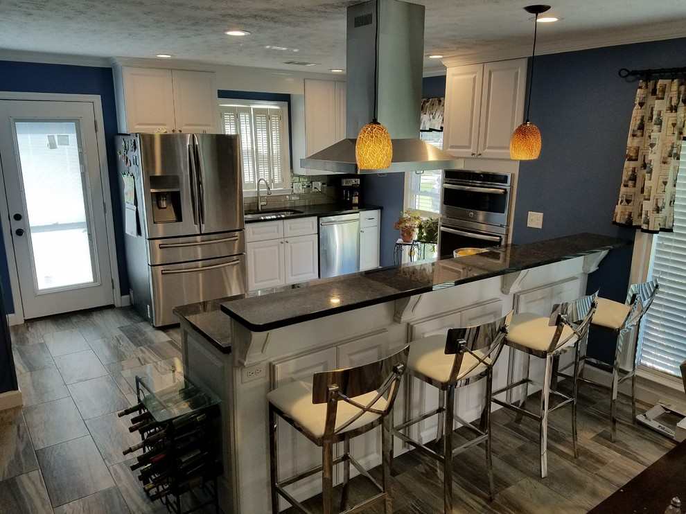 Example of a mid-sized transitional galley medium tone wood floor and beige floor eat-in kitchen design in Atlanta with an undermount sink, raised-panel cabinets, white cabinets, quartz countertops, beige backsplash, subway tile backsplash, stainless steel appliances and a peninsula