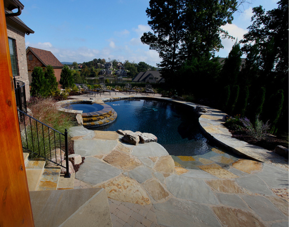 Inspiration for a large rustic backyard stone and custom-shaped lap hot tub remodel