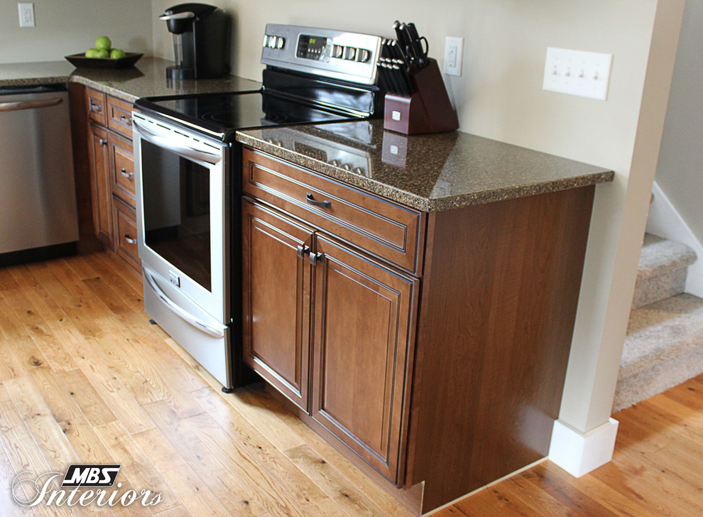 Inspiration for a transitional l-shaped kitchen remodel in Columbus with an undermount sink, recessed-panel cabinets, medium tone wood cabinets, quartz countertops, stainless steel appliances and an island